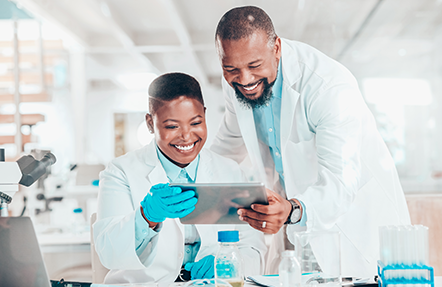 A man and a woman in a pharma manufacturing lab looking at a tablet together.